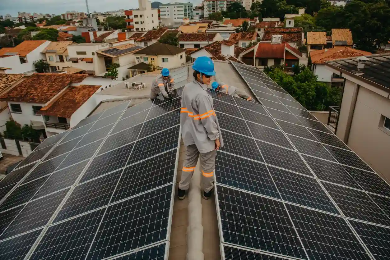 Equipe de técnicos instalando painéis solares em telhado de residência urbana, aproveitando energia renovável solar em cidade.